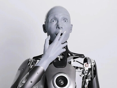 A robot covers his mouth with a human expression of surprise
