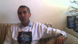 Carlo Di Litta resting comfortably on his sofa wearing a sweater that has an image of the cover of his book  "Cosa Nascondono I Nostri Governi?"