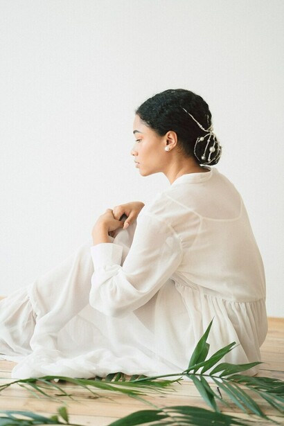 A woman in a long white dress sits in an empty room, embodying sustainable fashion with circular, eco-friendly, and biodegradable textiles
