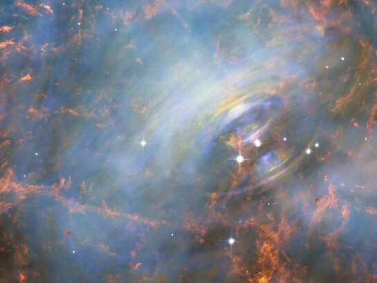 Mentre molte altre immagini della famosa Nebulosa del Granchio si sono concentrate sui filamenti nella parte esterna della nebulosa, questa immagine mostra il cuore stesso della Nebulosa del Granchio, compresa la stella di neutroni centrale — che è la più a destra delle due stelle luminose vicine al centro di questa immagine. Il rapido movimento del materiale più vicino alla stella centrale è rivelato dal delicato arcobaleno di colori presente in questa immagine realizzata con la tecnica del time-lapse; l’effetto arcobaleno è dovuto al movimento del materiale nel lasso di tempo che intercorre tra una foto e l’altra. Fonte NASA, ESA