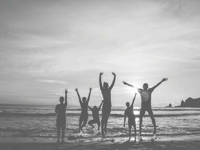 A group of people all with arms raised rejoicing on the beach their freedom and liberation