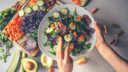 Female hands holding a bowl of vegan salad with fresh vegetables 