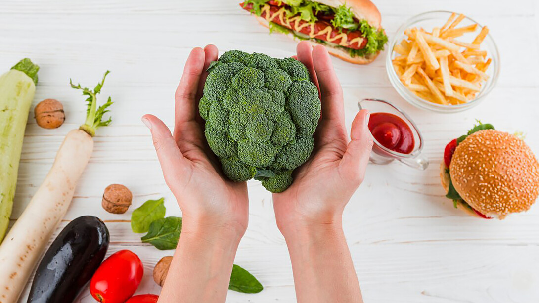 A hand holding fresh broccoli, a symbol of healthy eating and nutritional vitality