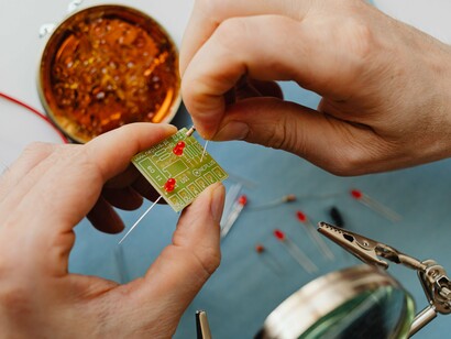 Hands assembling electronic components on a workbench, representing the human effort behind increasingly powerful technologies