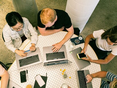 A group of colleagues with laptops sitting together 