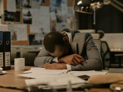 A man worn thin by exhaustion, reflecting the quiet burden carried within today’s workplace culture