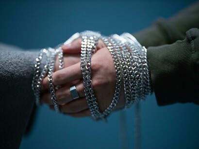 Hands exchanging a silver chain to express connection amongst both parties