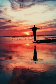 Channeling life with arms stretched out as the sun sets