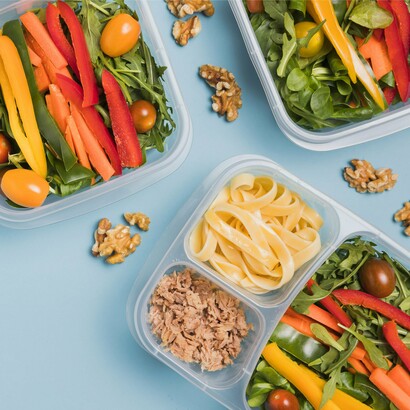 A rainbow of greens, grains, and proteins in individual boxes highlights the variety now essential to athlete fueling