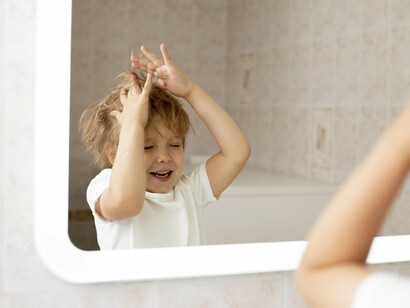 Un bambino gioca con i capelli davanti allo specchio. Il processo di autoriconoscimento non è lineare e può essere influenzato da molteplici fattori, tra cui l'ambiente familiare, culturale, educativo e le esperienze di vita