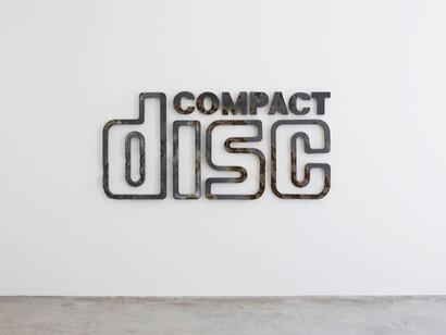 View of the exhibition Daniel Arsham “The Future
is Always Now”, Galerie Perrotin, Paris, June 12 - July
26, 2014. "Steel Eroded Compact Disc Sign" 2014, Steel fragments, volcanic glass, hydrostone, 109 x 232 x 5 cm / 43 x 91 1/4 x 2 inches, Photo : Claire Dorn
Courtesy Galerie Perrotin