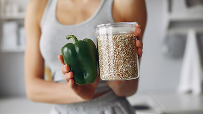 A woman prepares sustainable protein and fresh vegetables in kitchen