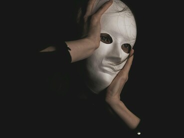 A person holding on tightly to the mask, showing how power is often used from behind veils of secrecy