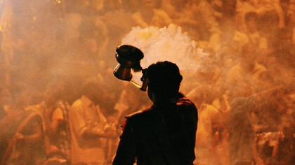 Ragazzo nella folla solleva contenitore con polvere colorata a Mumbai, in India