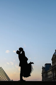 Silhouette of a man lifting a woman in his arms near the Louvre Museum in Paris, France