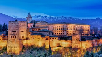 At dawn, the Alhambra Palace in Granada, Spain, stands gracefully near the snow-capped Sierra Nevada mountains, Spain
