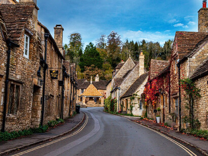 A street lined with stone buildings adjacent to a forest in the charming village of Castle Combe, Chippenham, UK