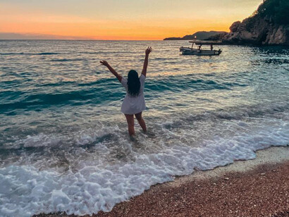 A woman enjoys the natural beauty of the Montenegro coastline at sunset