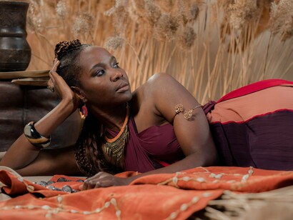A woman resting among traditional textiles and handcrafted adornments, representing how cultural identity is shaped by both roots and exchange