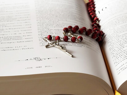 A rosary resting on the pages of an opened Bible book