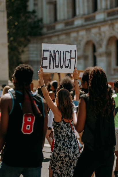 Una mujer con un cartel que dice "Suficiente" en una protesta