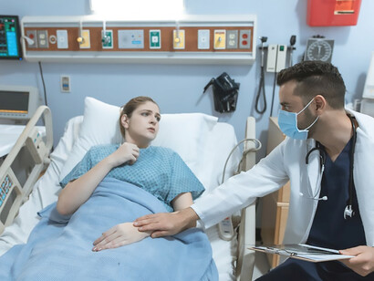 A woman, battling illness, lies on a hospital bed, tears streaming down her face