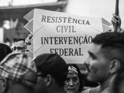 Plano cerrado de una pancarta, entre anifestantes brasileños en una protesta pacífica con una gran y diversa multitud