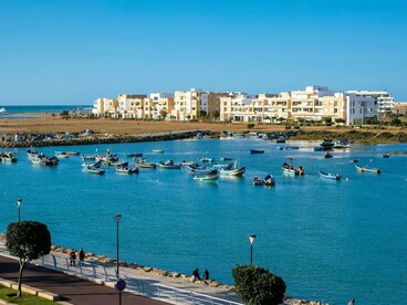 Boats scattered across the Bouregreg waterfront in front of Rabat’s contemporary architecture, reflecting the continuity of Moroccan identity through changing times