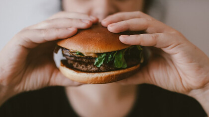 A person holding a large, juicy burger with both hands