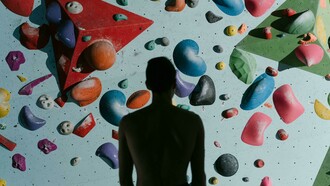 A silhouette of a man standing before a climbing wall, preparing to climb