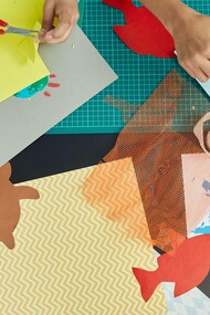 A group of people using scissors and pens to create handmade crafts out of paper
