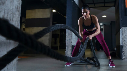 A fitness woman performing a workout with battle ropes in the gym