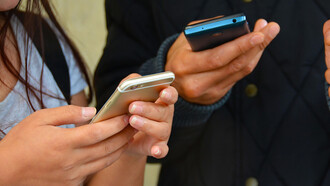 Two individuals utilizing mobile phones and technology