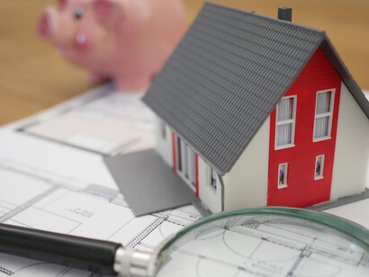 On a rustic brown table, you'll find a charming miniature house, beautifully painted in white and red