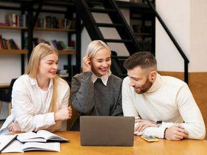 A group of colleagues studying and collaborating in a library, using laptops to dive into the concepts of innovation, digital transformation, and the knowledge-based economy