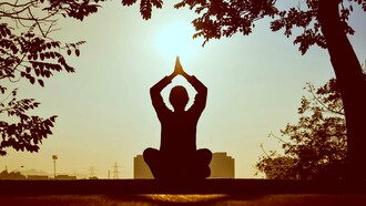A silhouette of a person practicing yoga at sunrise, surrounded by nature’s tranquility