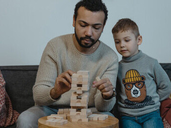 Pai e filhos desfrutam de um jogo de estratégia, desafiando a narrativa tradicional da educação com diversão e interação familiar
