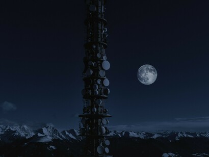 A communications tower stands against the night sky with the moon in view, evoking the role of electromagnetic signals and atmospheric conditions in identifying aerial anomalies
