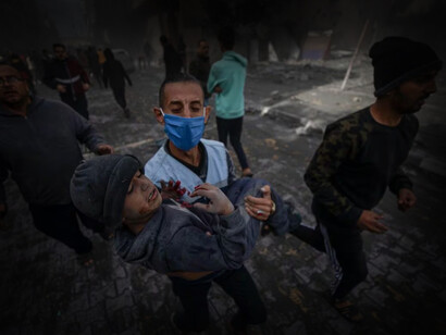 Un hombre carga un niño herido en brazos durante un ataque en la región de Gaza