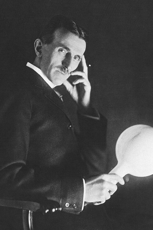 Nikola Tesla holding a gas-filled phosphor coated wireless light bulb which he developed in the 1890's, half a century before fluorescent lamps come into use