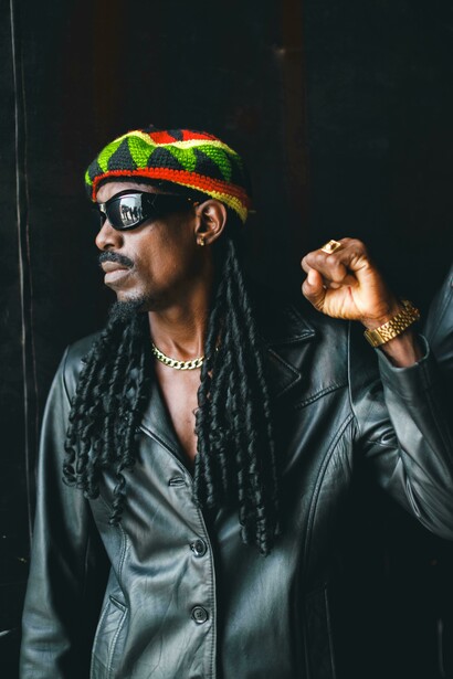 Portrait of a man wearing sunglasses and a hat, evoking classic reggae style
