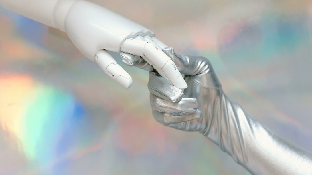 A gloved hand holding a robotic hand 