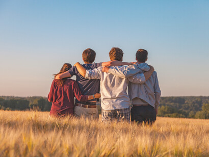 Grupo de amigos se abrazan en una pradera