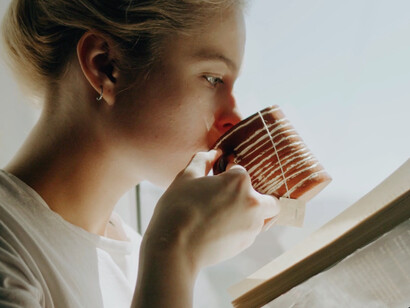 The warm cup of tea cradled in her hands symbolises a mindful pause, inviting reflection amidst the bustle of modern life