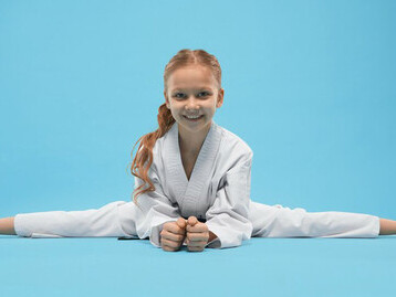 A girl in a white kimono making twine while lying on a blue background symbolizes the balance a student-athlete must maintain, managing time for both sports and academics, as she studies and prepares for a sports scholarship