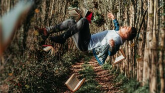A foto de capa mostra um homem aparentemente flutuando em uma trilha de bosque, cercado por livros abertos suspensos no ar. A composição cria uma atmosfera surreal, remetendo à imaginação, ao acaso e ao poder das ideias, o que dialoga com a reflexão do artigo sobre coincidências improváveis e os limites da lógica. A imaginação muitas vezes alcança lugares onde a lógica e a estatística não conseguem chegar. Assim como na narrativa, a realidade às vezes desafia qualquer cálculo de probabilidade
