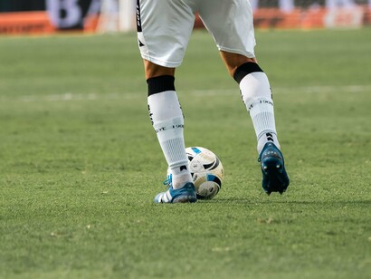 De costas para a câmera, um jogador conduz a bola pelo gramado. No futebol profissional, a leitura do jogo e a capacidade de encontrar espaços são fundamentais para construir oportunidades e contribuir com a equipe. Para Gabigol, o retorno ao Santos representa o desafio de voltar a demonstrar essas qualidades e recuperar seu protagonismo