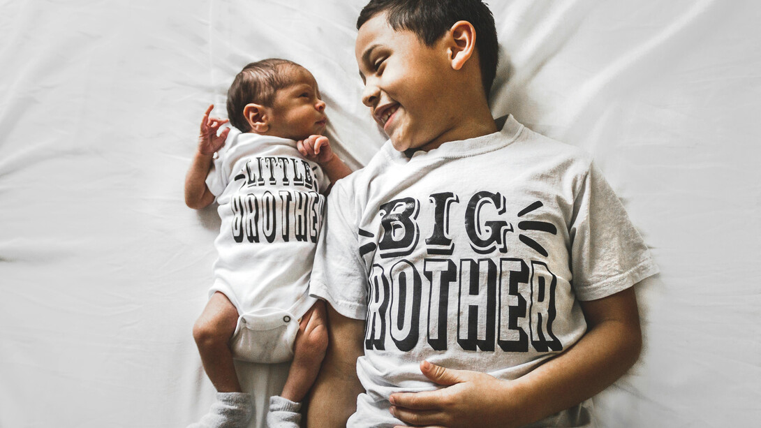 Newborn baby beside his older brother in a photograph