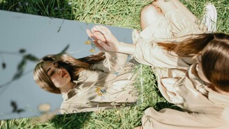 A woman next to a mirror with a pensive expression, reflecting the weight of unkind thoughts
