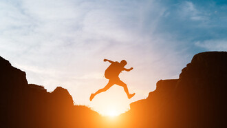 As the sun sets behind him, the man leaps across the rocks, embracing the journey, not just the destination, in his pursuit of personal growth